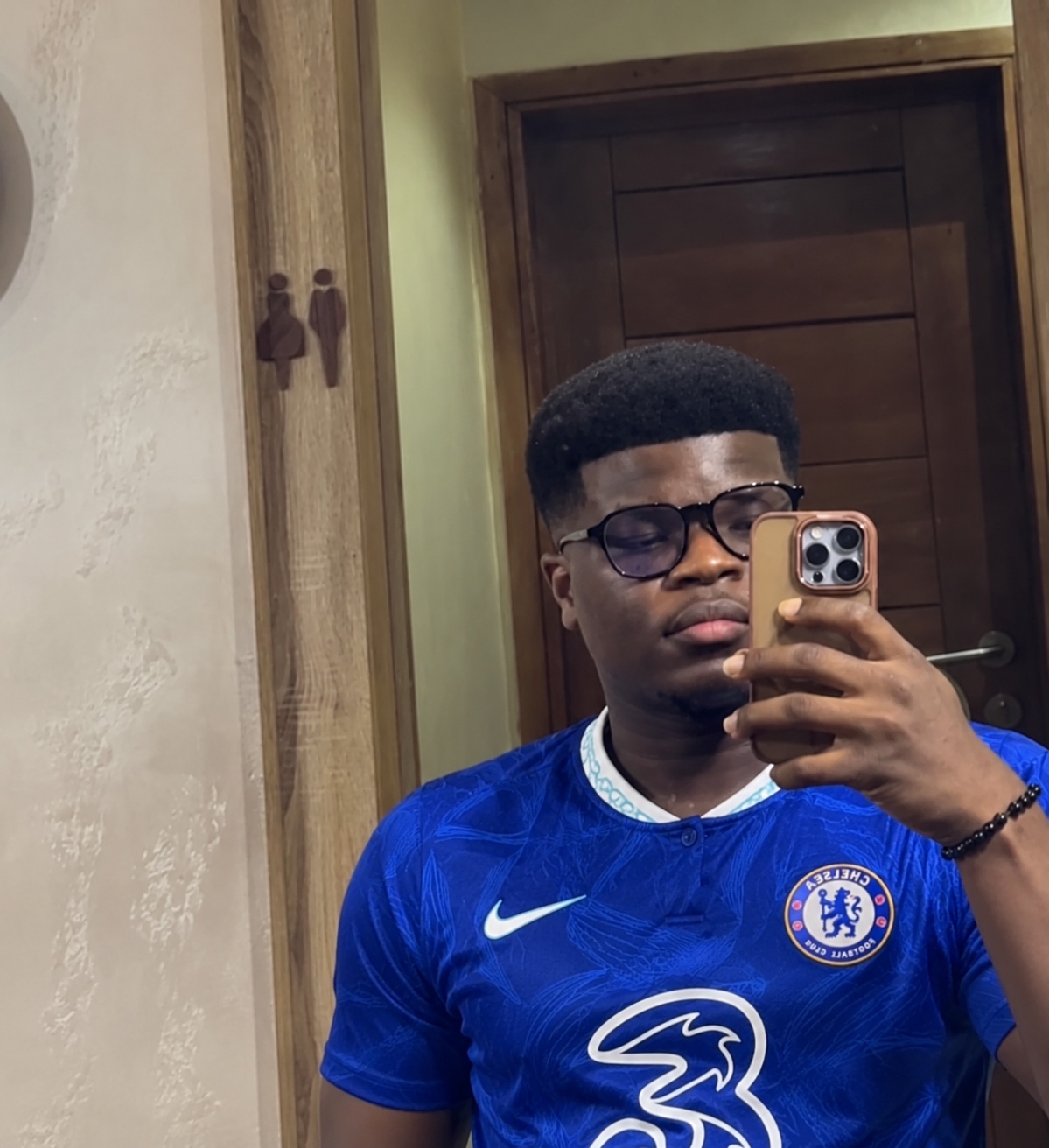 Okiki taking a mirror selfie in his Chelsea football shirt